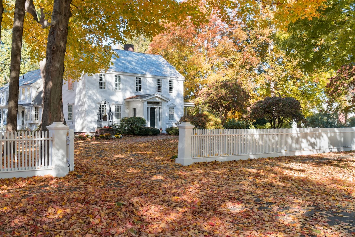 Exterior of an older home during autumn with leaves on the ground