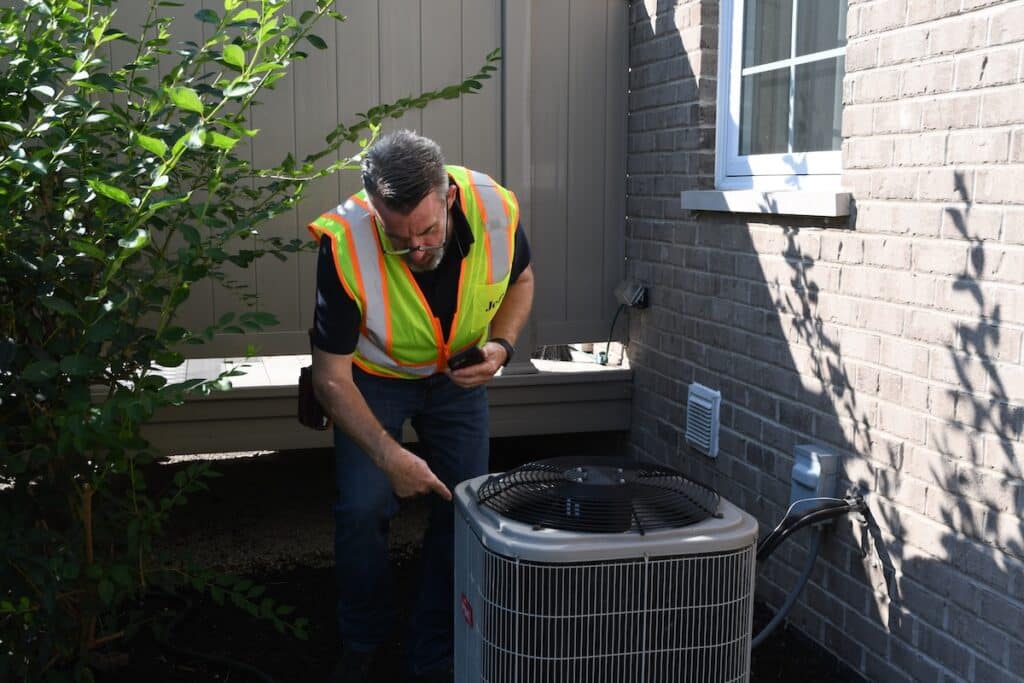 A home inspector inspecting the condenser unit outside of a home