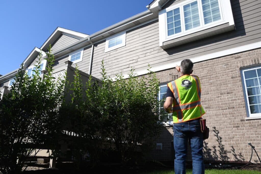 A home inspector pointing at the exterior siding on the second story during a 1 year builder's warranty inspection