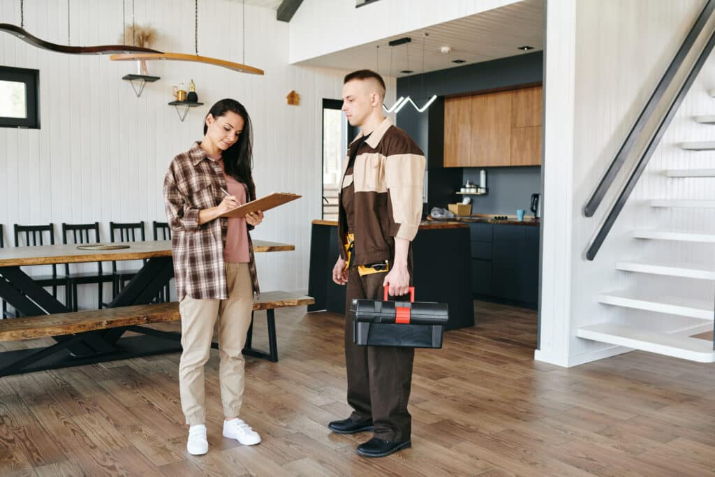 Young woman signing paper after receiving plumbing service while standing in front of plumber